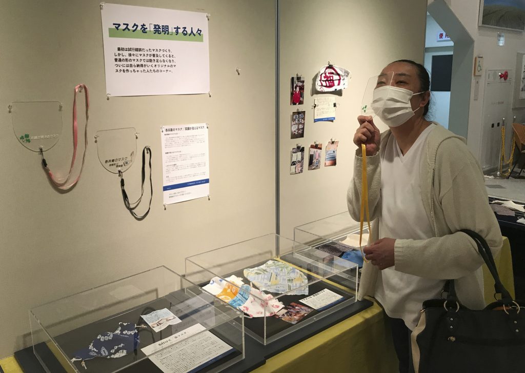 浦幌町立博物館の学芸員、持田誠氏が提供した写真。2020年8月14日、北海道にある同博物館で、保育園の調理師・前出彰子さんが展示されたマスクを見ている。同博物館では、コロナウイルスの大流行で生活がどのような影響を受けたかを正確に記録しようと、チラシやテイクアウトのメニュー、マスクなどの日常の品を収集している。（AP）