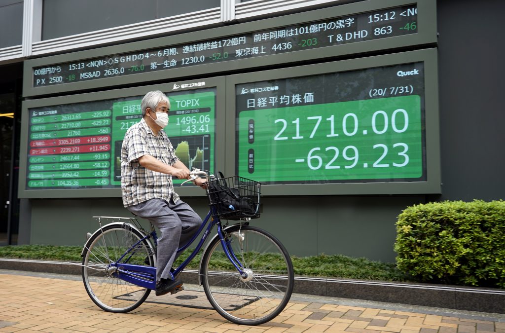 東京で株価ボードの前を自転車で通り過ぎるマスクを着用した男性。2020年7月31日。（資料写真/EPA）