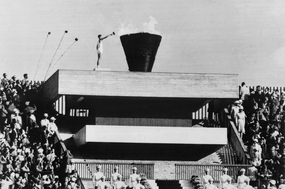 1964年10月10日に撮られた写真には、1964年の東京オリンピック大会の開会式で、聖火台に火を付ける日本の聖火ランナー、坂井義則が写っている。（AFP通信／資料）