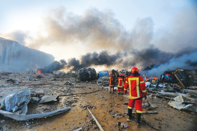 レバノンの首都を揺るがした2つの大爆発で煙が空に吹き上がり、数マイル先の建物を損傷させた後、消防隊員とショックを受けた見物人が瓦礫の下に閉じ込められた人々を捜索する（AFP）