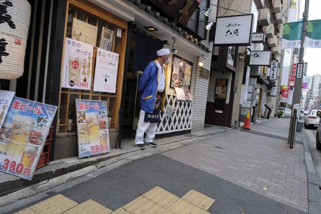 東京駅近くの閑静な通りにあるレストランで、客待ちをするレストランの従業員。（AFP）