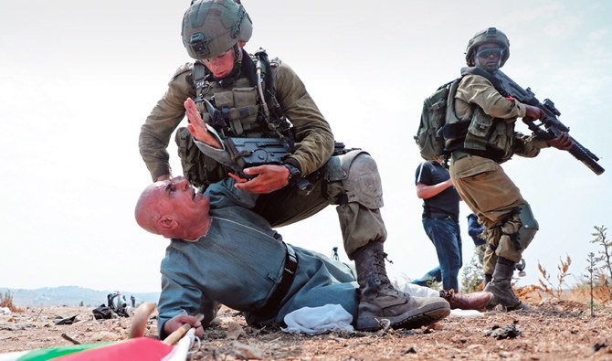 占領されているヨルダン川西岸のトゥルカルムで行われたイスラエルの植民地計画に反対するデモ運動中にパレスチナ人抗議者を押さえつけるイスラエル兵。（AFP）