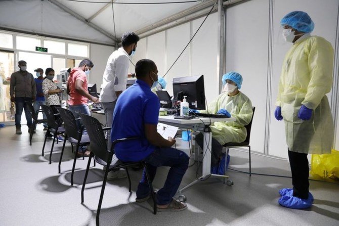 アラブ首長国連邦のアブダビにあるクリーブランド・クリニック病院で、防護具を着用した医療スタッフが患者に新型コロナの検査を実施している。（資料/ロイター）