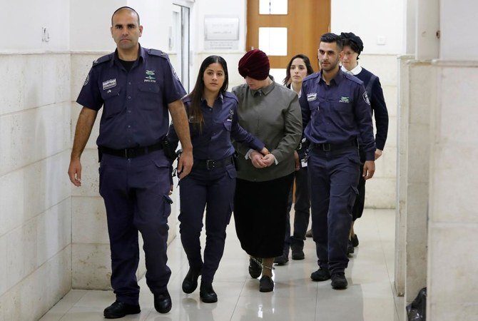 かつてオーストラリアで教師をしていたマルカ・レイファー（中央）がエルサレムの地方裁判所での聴聞のために到着し、警察に同行される。（AFP ファイル写真)