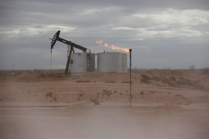 テキサス州ラビング郡のパーミアン・ベースンにある原油ポンプジャックの周りを土ぼこりが舞い、掘削パッドから余剰ガスが燃え上がる。（ロイター/ファイル写真）