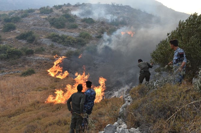 2020年9月8日、国営シリア・アラブ通信社（SANA）公開の配布資料写真。ハマー県西部の田園地帯にある、アインハラキム村で火災発生中の丘を歩く治安部隊。（AFP）