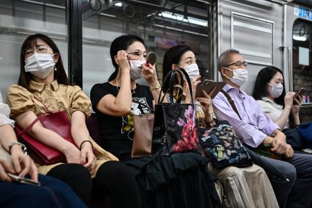 東京では電車で通勤しながらマスクを着用。(AFP)