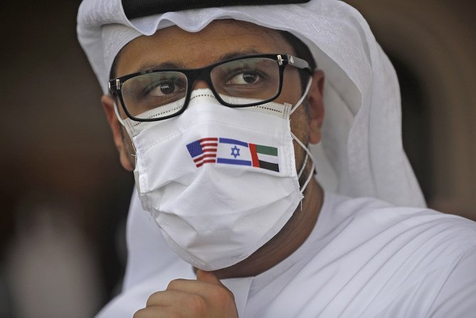 国交正常化合意後、米-イスラエルの代表団を乗せ、イスラエルからUAEに向かう最初の商用便の到着後、アブダビ空港で、米国、イスラエル、UAEの国旗が描かれた防護マスクを着用したUAEの男性。（2020年8月31日撮影、AFP）