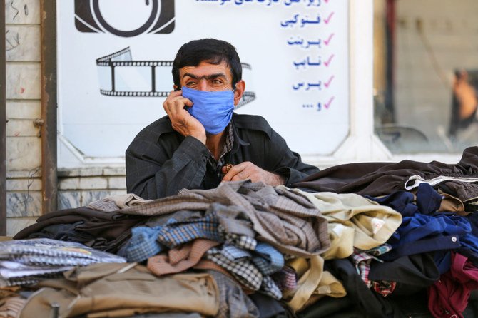 イランの西アゼルバイジャン州の町サルダシュトで客を待ちつつ、電話で話すイラン系クルド人の露天商人（2020年9月14日撮影）。（AFPの写真）