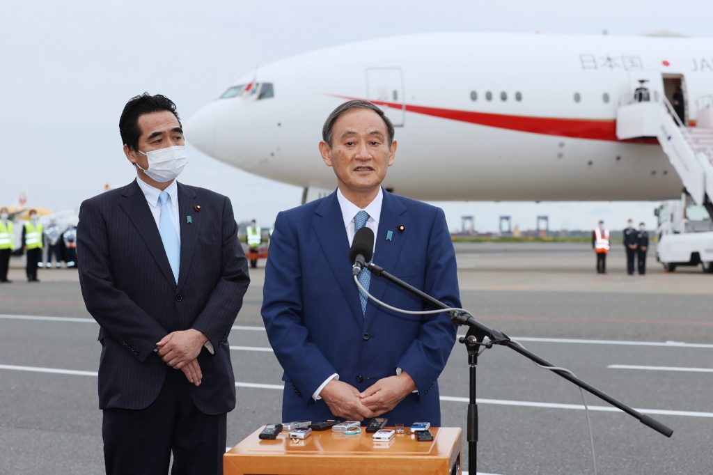 就任後初の外国訪問に先立ち、報道陣の取材に応じる菅義偉首相（右）＝１８日午後、羽田空港 (AFP)