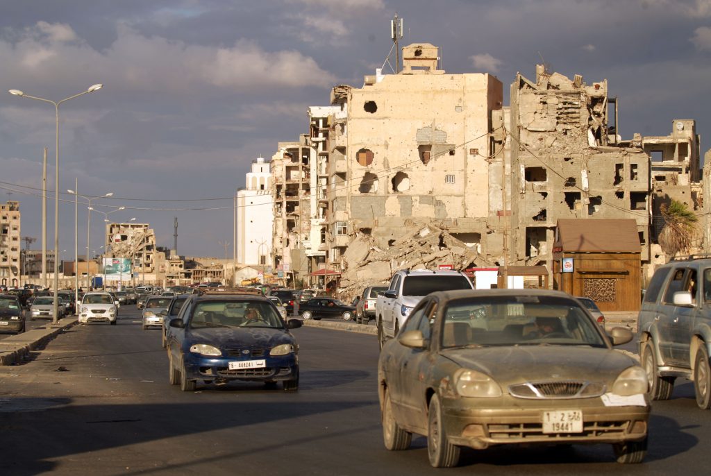 2020年10月23日、リビアの内戦中の勢力間で停戦協定が調印された後、リビア北東部に位置する港湾都市、ベンガジにある砲弾を受けた建物の近くを運転する自動車。 （AFP）