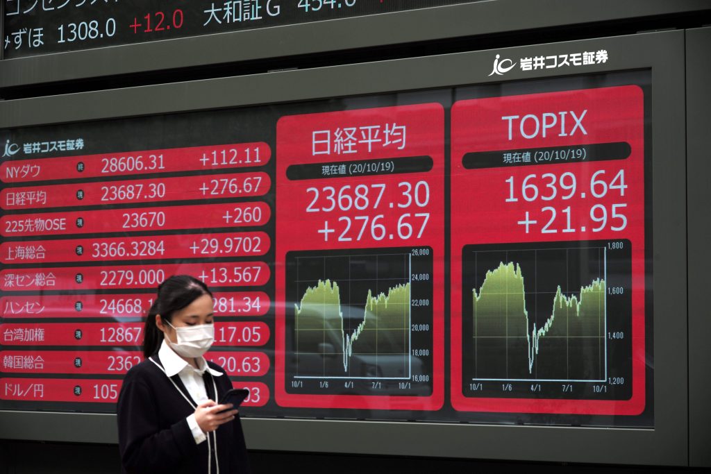 2020年10月19日、東京証券取引所(C)の株価を表示する電子掲示板の前を歩く女性。(AFP)