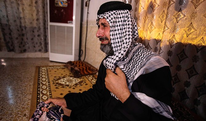 イラクのアマラにある自宅で、拉致された抗議運動家Ali Jasbさんの写真を持って泣く、父親のJasb Hattab Aboudさん。（AP）