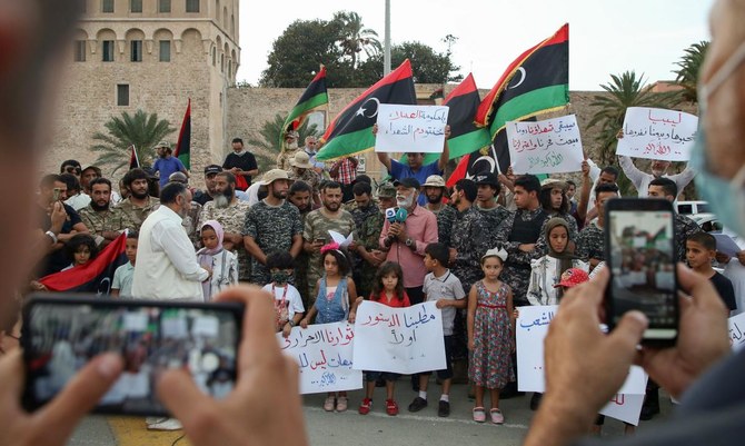 2020年10月2日、トリポリの殉教者広場の集会で、リビアの政治、防犯、生活の状況悪化に抗議して、デモ隊がプラカードと国旗を掲げている。（AFP）