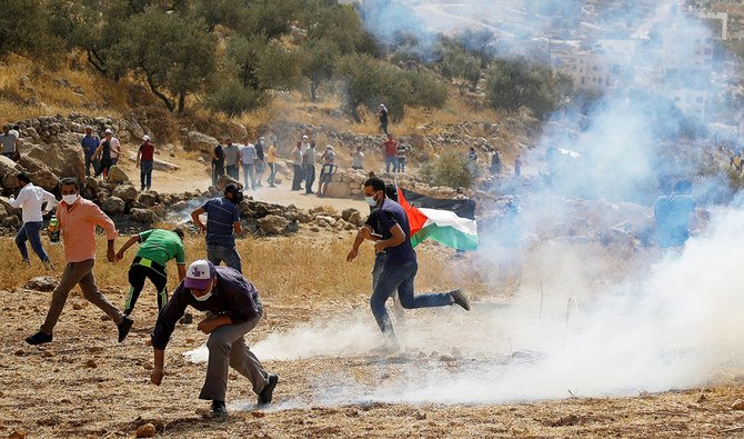 ユダヤ人入植地に対する抗議活動中、イスラエル軍によって発射された催涙ガスから逃げるパレスチナ人。金曜日、西岸のナブルス近郊。（ロイター）