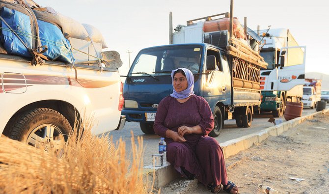 イラクのドホーク近郊でコロナウイルス（COVID-19）流行と経済危機のため、シンジャールに戻る途中で道路に座る避難民の女性。（ロイター）