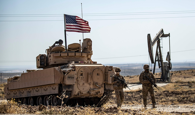 シリア・ハサカ県アル＝マーリキーヤ市近くの田舎での軍事パトロール中にブラッドレー戦闘車そばを歩くアメリカ兵、火曜。（AFP）