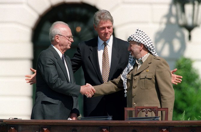 1993年9月13日、ワシントンDCのホワイトハウスで、PLOのヤセル・アラファト議長（右）とイスラエルのイツハク・ラビン首相（左）が初めて握手を交わす中、2人の間に立つビル・クリントン大統領（中央）。（写真：J. DAVID AKE/AFP通信）