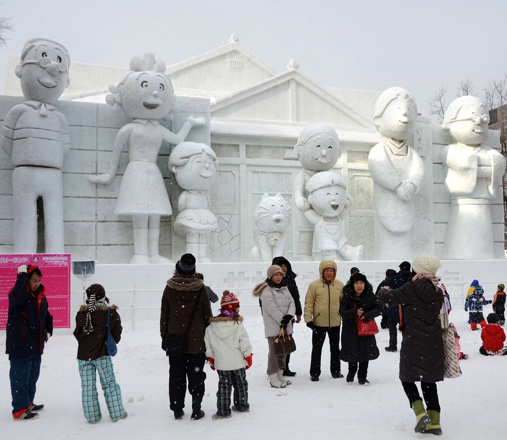 毎年恒例の雪まつりで、日本のアニメや漫画で親しまれているサザエさんの漫画キャラクターの大きな雪像を鑑賞する人々。北海道札幌、2011年2月7日。作曲家筒美京平は「サザエさん」のテーマソングの作曲を担当した。(AFP)