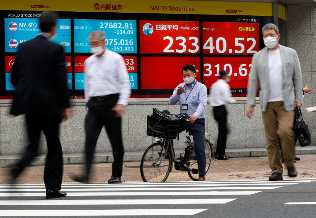 新型コロナウイルス(COVID-19)禍の中、日経平均株価や海外の株価指標を表示する証券会社のディスプレイの前を通り過ぎる防護マスクを装着した通行人たち。東京、日本。2020年10月5日。(資料写真/ロイター)