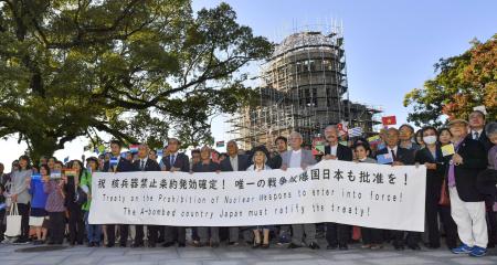 2020年10月25日(日)、西日本に位置する広島で原爆ドームを背景に、日本政府に核兵器禁止条約の批准を求める旗を掲げる原爆被爆者団体のメンバー。(AP=共同通信)