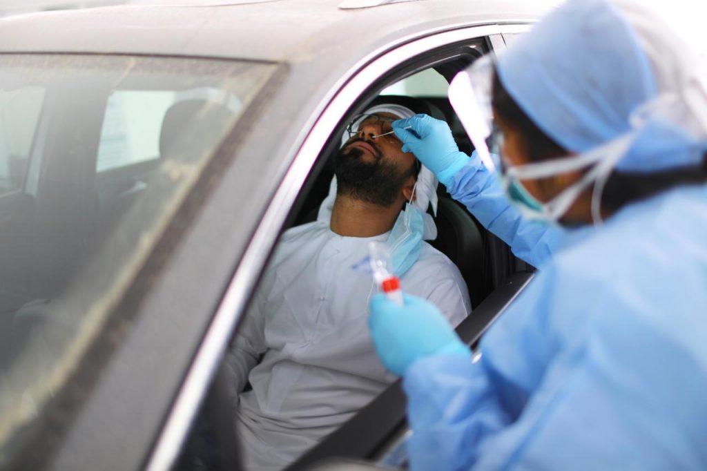2020年3月30日、UAEのアブダビ、COVID-19のドライブスルー検査で、医師が男性に綿棒で検体を採取する。（ロイター通信）