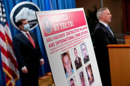 指名手配のロシア軍諜報将校6名が掲載されたポスター。アメリカ・ペンシルバニア州西部のスコット・ブレイディ（Scott Brady）検事（右）は国家安全保障課のジョン・デマーズ（John Demers ）検事総長補佐(左）を同席し、2020年10月19日、ワシントンDCの法務省報道会見で語った。（AFP）
