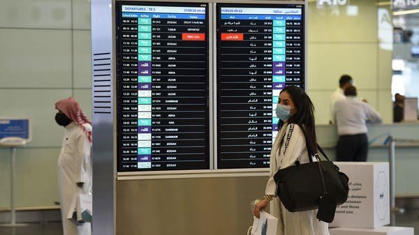 防護マスクを付けてキング・ファハド国際空港に到着する乗客。（AFP）