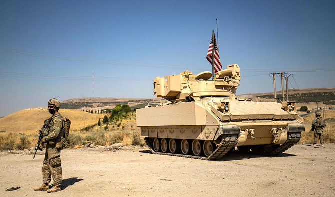 2020年10月5日、シリアのクルド人が支配している北東部ハサカ県にあるルメイラン油田周辺でパトロール中に装甲戦闘車のそばに立つ米兵。（AFP）