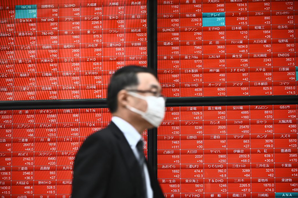 東京証券取引所の株価を表示する電子株価ボードの前を通り過ぎる男性。2020年11月24日、東京にて撮影。（AFP）