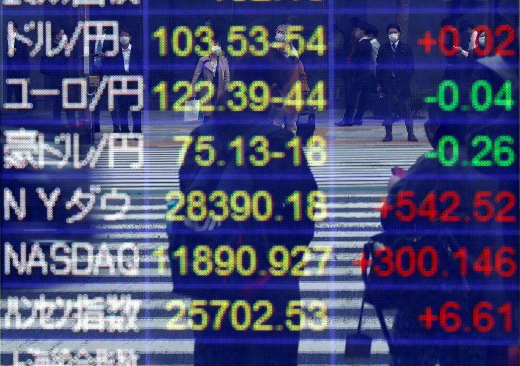 コロナウィルス感染症(COVID-19)が大流行する東京で、証券会社の外にある対ドル円相場やその他の通貨、世界の株価指数を表示する画面に映り込む、マスクを着用した通行人。2020年11月6日。(ロイター)