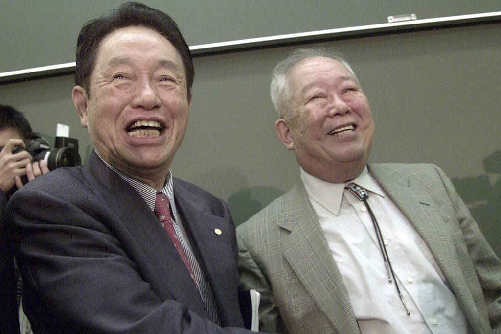 2002年にノーベル物理学賞を受賞した後、東京の東京大学で、1973年に同じ賞を受賞した江崎玲於奈に祝福される日本人物理学者小柴昌俊（右）。2002年10月8日撮影の資料写真。宇宙の成り立ちに対する先駆的な研究でノーベル賞を共同受賞した小柴が2020年11月12日木曜に死去したと、大学が発表した。94歳だった。（AP）