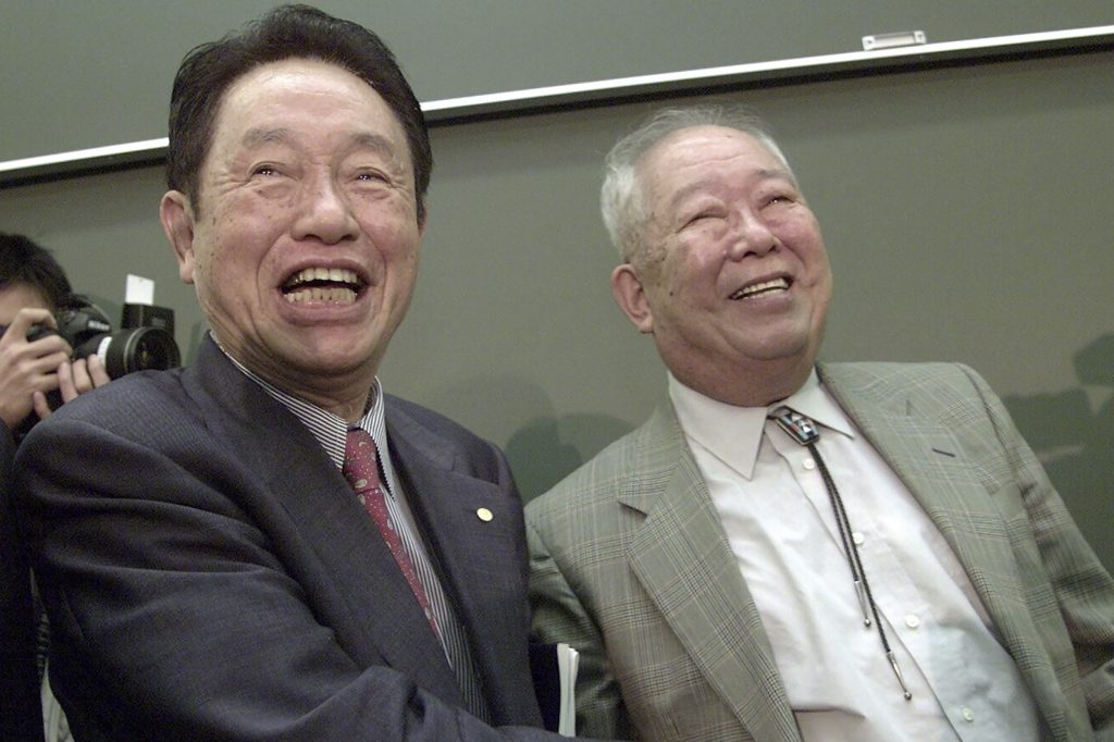 2002年にノーベル物理学賞を受賞した後、東京の東京大学で、1973年に同じ賞を受賞した江崎玲於奈に祝福される日本人物理学者小柴昌俊(右)。2002年10月8日撮影の資料写真。宇宙の成り立ちに対する先駆的な研究でノーベル賞を共同受賞した小柴が2020年11月12日木曜に死去したと、大学が発表した。94歳だった。(AP)