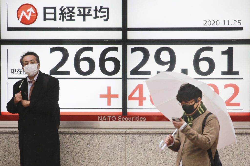 日本の日経225指数を表示する東京の証券会社の電子株価ボードの脇に立つ人々。2020年11月25日水曜撮影。（資料写真/AP）