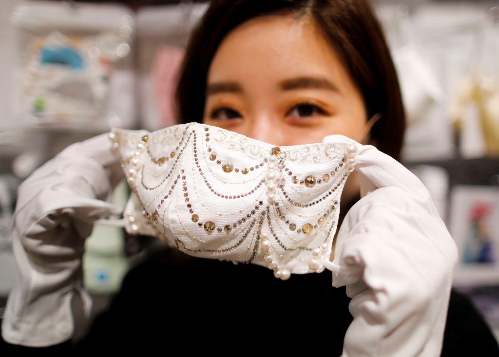 2020年11月25日の東京、コロナ禍の最中、コックス社経営のマスク専用ショップMask.comで、ダイヤ、プラチナ、スワロフスキークリスタルで飾られた100万円(9,640ドル)の高級マスクを披露する従業員。(File photo/Reuters)