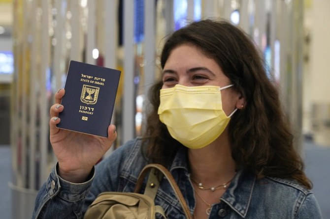2020年11月26日木曜日、テルアビブ発フライドバイ便のイスラエル人乗客が、アラブ首長国連邦ドバイにあるドバイ国際空港に到着早々、自分の持っていたイスラエルのパスポートをちらつかせる。（AP通信）
