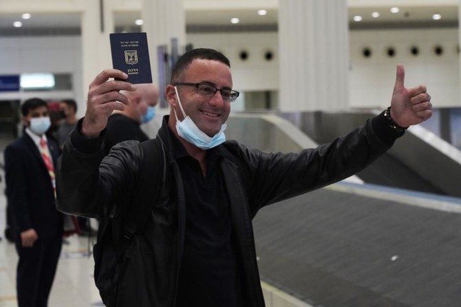 2020年11月26日木曜日、テルアビブ発フライドバイ便のイスラエル人乗客が、アラブ首長国連邦ドバイにあるドバイ国際空港第3ターミナルに到着早々、自分の持っていたイスラエルのパスポートをちらつかせる。（AP通信）
