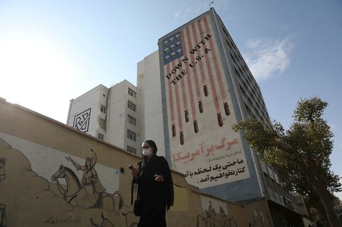 イラン・テヘランの建物に映し出された反米的な映像の側を歩く女性。（WANA／ロイター通信）