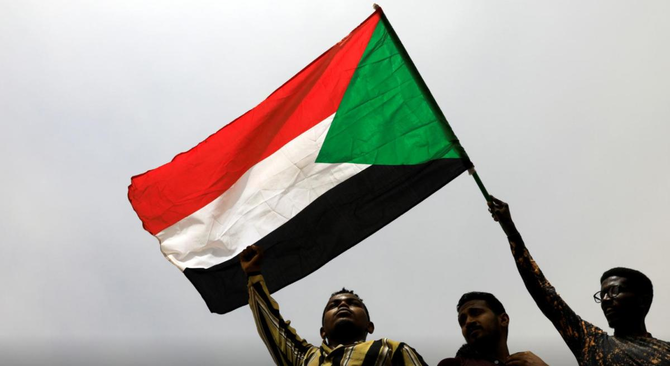 スーダンの国旗を掲げるデモ参加者たち。（ロイター）