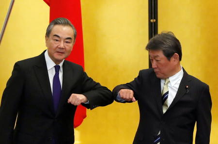 2020年11月24日、東京で新型コロナウイルス感染症（COVID-19）の感染が拡大する中、会談の開始時に「肘タッチ」を交わす中国の王毅国務委員兼外相（左）と日本の茂木敏充外務大臣。（ロイター）