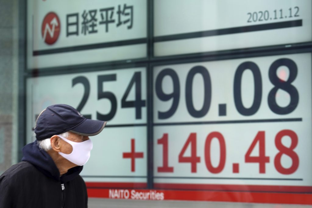 東京の証券会社の前を、日経平均株価の速報を眺めながら通り過ぎる男性。(2020年11月12日、ファイル写真=AP)