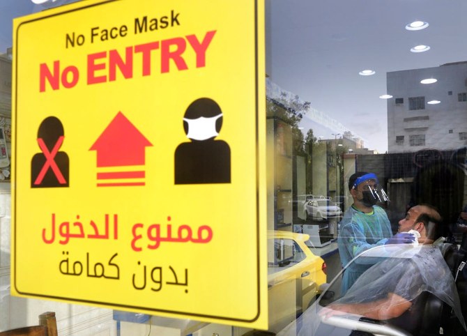 新型コロナウイルスの蔓延を抑えるための健康的な手順を示すポスターが貼られたサウジアラビアのジッダにある理髪店の窓。（AFP）