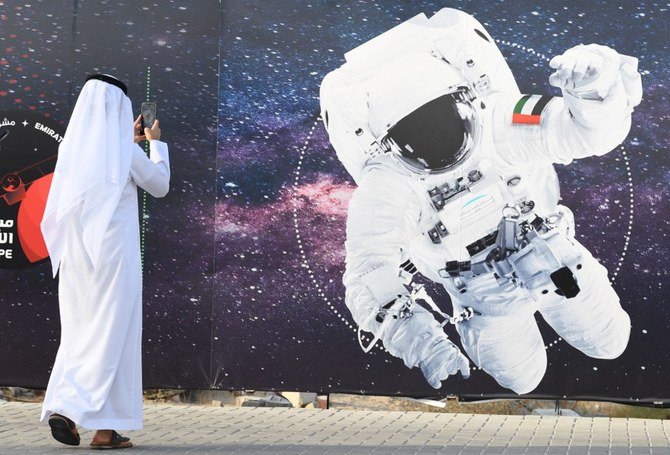 男性が2019年9月25日にドバイのムハンマド・ビン・ラーシド宇宙センター（MBRSC）の外で宇宙飛行士と首長国の国旗を描いているイラストの写真を撮っている。（提出資料/AFP）