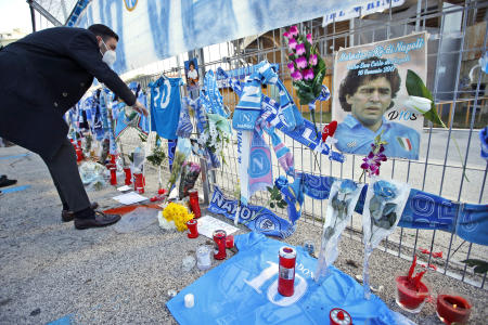 ディエゴ・マラドーナを追悼してサン・パオロ・スタジアムの外に飾られた品々を見つめる男性。イタリア南部のナポリで。（AP通信）
