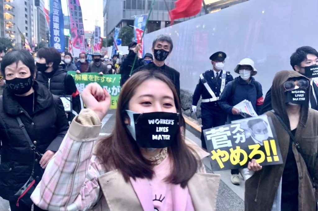 菅義偉首相の辞任を求める小さな横断幕を掲げるデモ参加者たちもいた