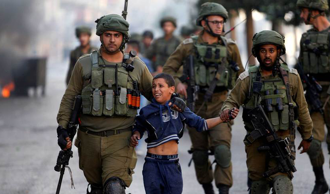 ヨルダン川西岸の都市ヘブロンでの衝突の中、パレスチナ人の少年を拘束するイスラエル兵士（Reuters/File）
