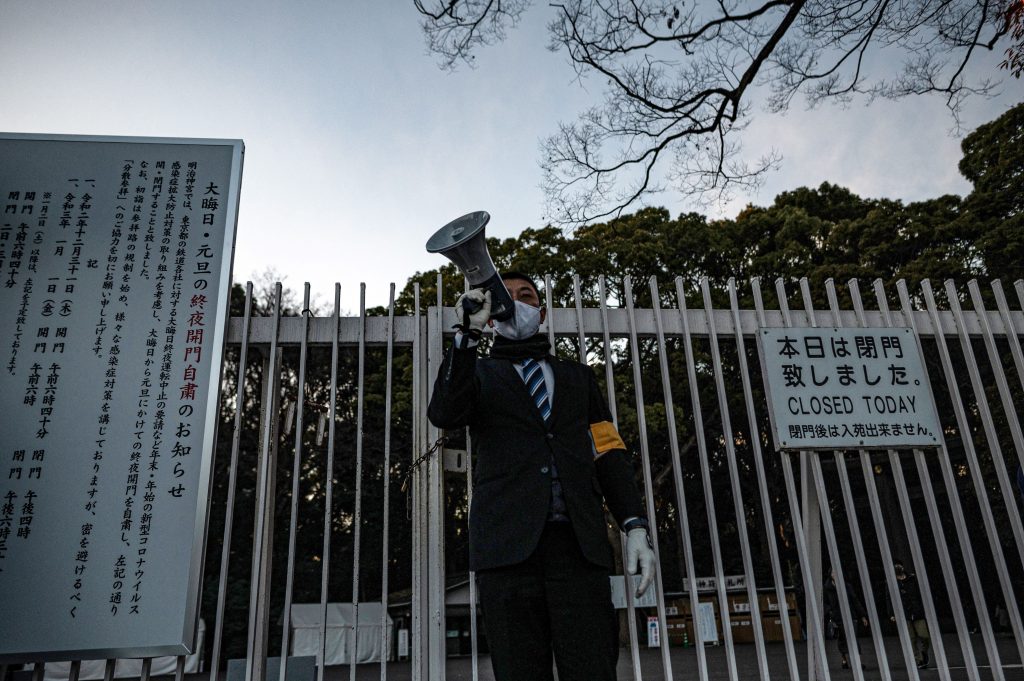 2020年12月31日、東京の明治神宮で、メガホンを使って例年より早く閉まると告げる神社のスタッフ。（写真提供：Philip FONG / AFP）