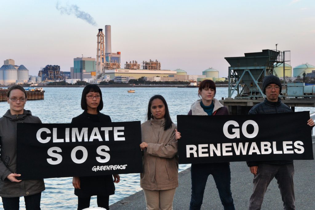 東京近郊の横浜の東京電力（TEPCO）とJパワーの火力発電所前で横断幕を掲げて地球温暖化に講義する環境団体グリーンピースのメンバーたち。2014年3月24日撮影。（AFP）