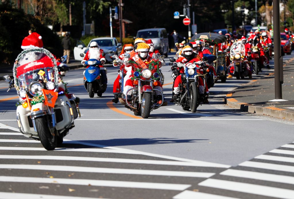 2020年12月20日、日本の東京で、コロナウイルス感染症（COVID-19）が発生する中、ハーレーサンタCLUBが主催し、休日気分を盛り上げて児童虐待に反対する集会を行うためのクリスマス・トイランのパレード中にバイクに乗るサンタクロースの衣装を着た人々。（ロイター通信）