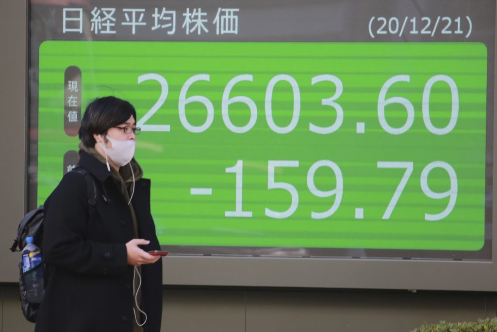 2020年12月21日（月）、東京都内にある証券会社の電子株価ボードの前を歩く男性。（資料写真/AP通信）